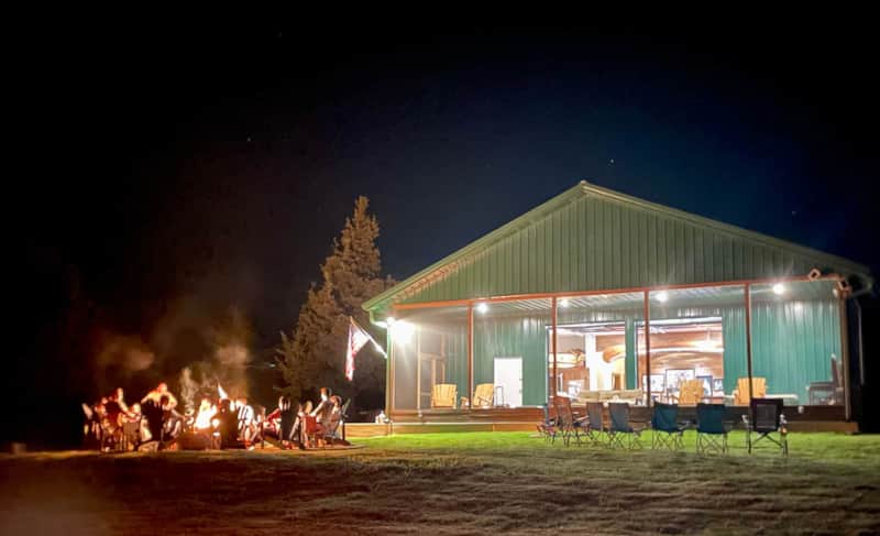 RustedFish Ranch cabin at night with guests around the fire pit